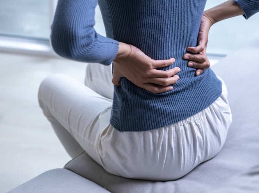Woman suffering from back ache on the sofa. Female with back pain at home.
